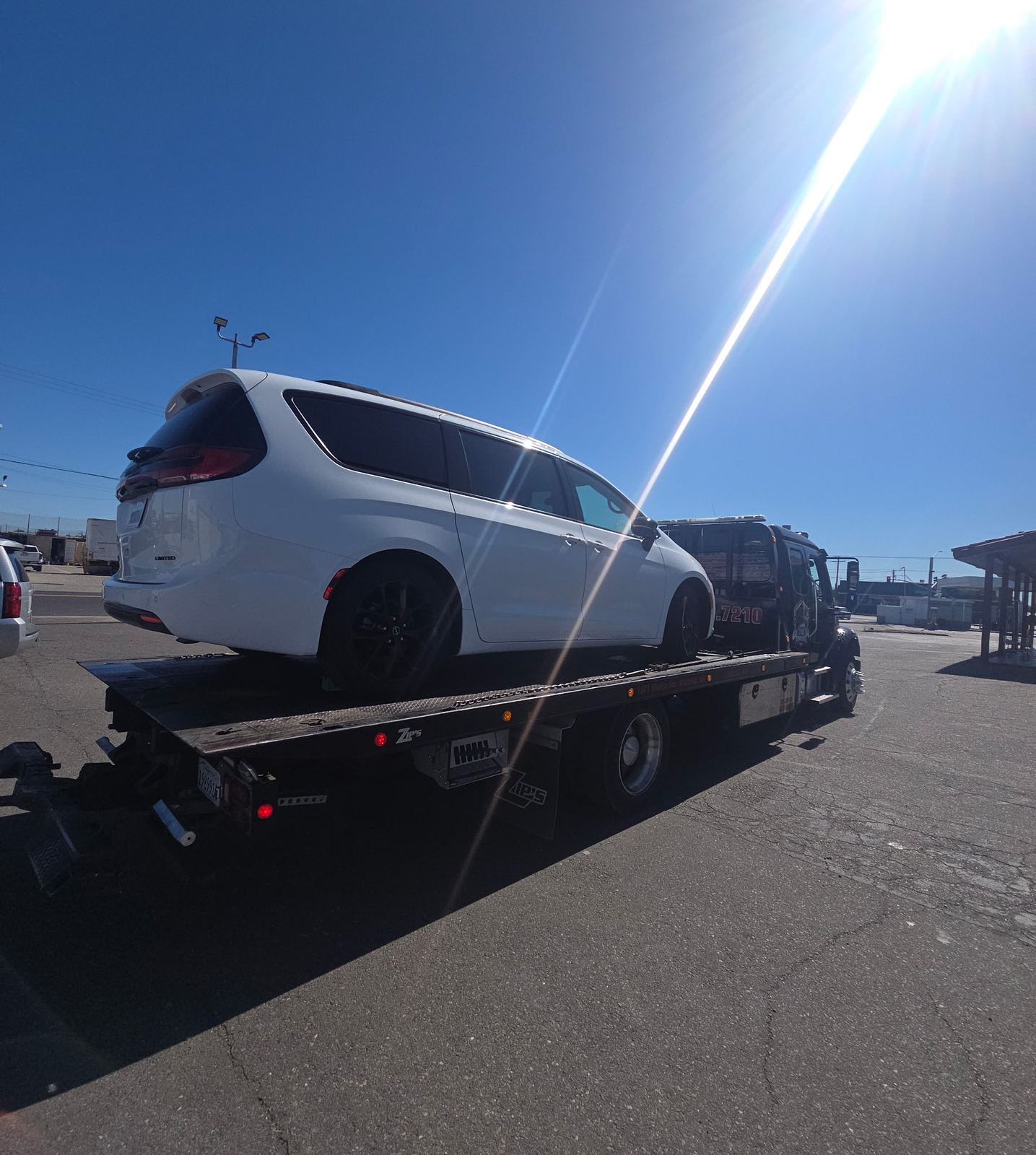White minivan being transported on a flatbed tow truck